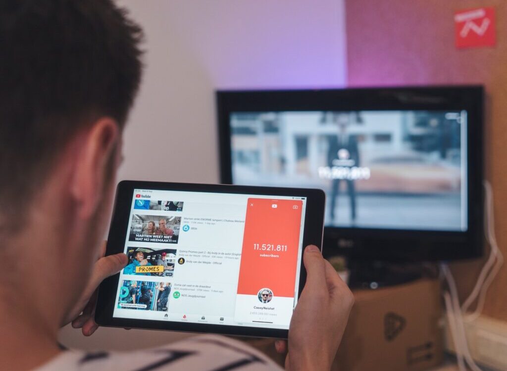 man browsing tablet sitting in front of TV