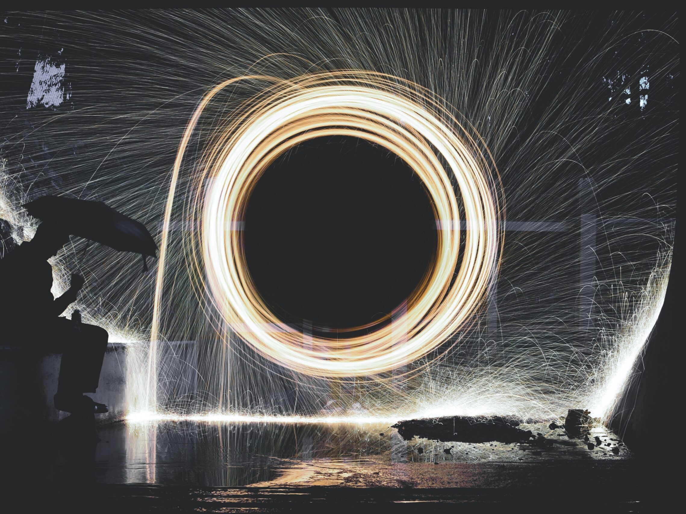 photo of person holding umbrella near steelwool during nighttime