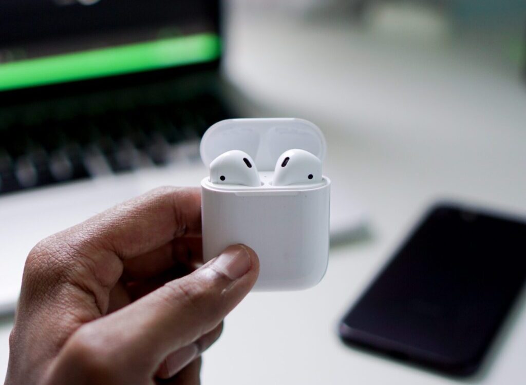 person holding wireless earbuds with charging case