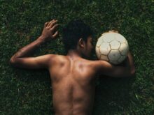 topless man lying on green grass field