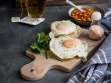 two fried eggs on brown chopping board near spices
