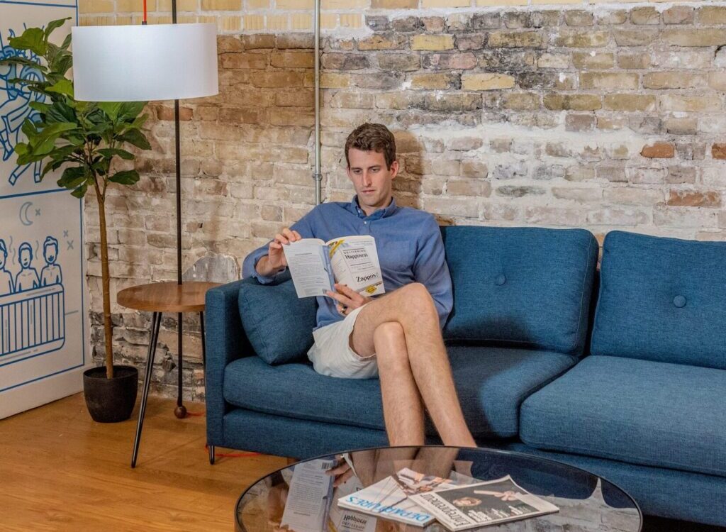 man sitting on blue sofa while reading book