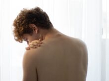 topless man standing near white curtain