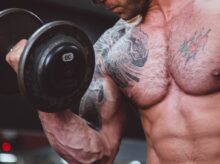 topless man holding black dumbell on right hand