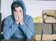 man covering face with both hands while sitting on bench