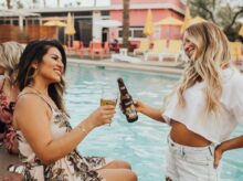 woman on pool tosing liquor with woman at daytime