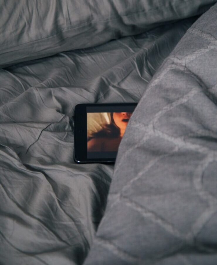 black Android smartphone on gray bed sheet