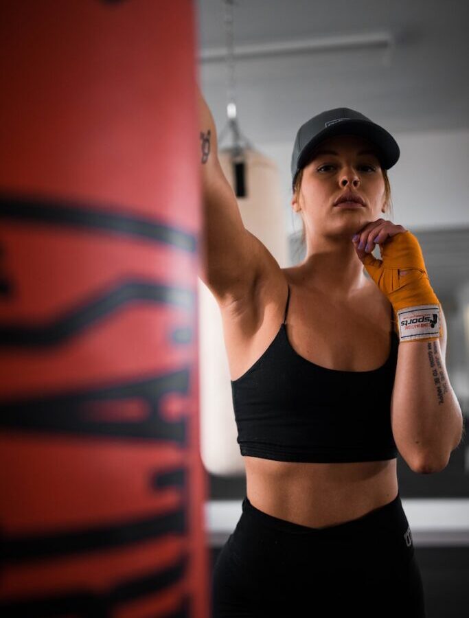 woman in black sports bra and black shorts holding orange bottle