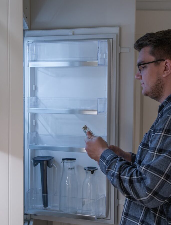 man in blue and white plaid dress shirt holding clear glass bottle