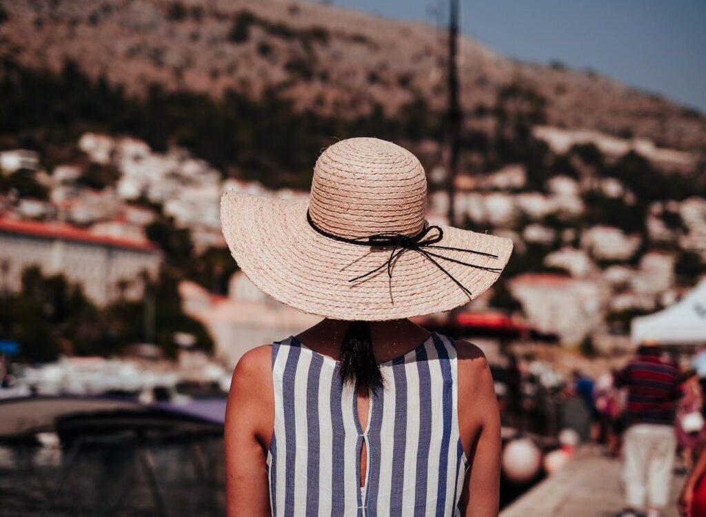woman wearing gray and white striped sleeveless top and brown sun hat at daytime