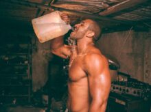 topless man drinking water from plastic container