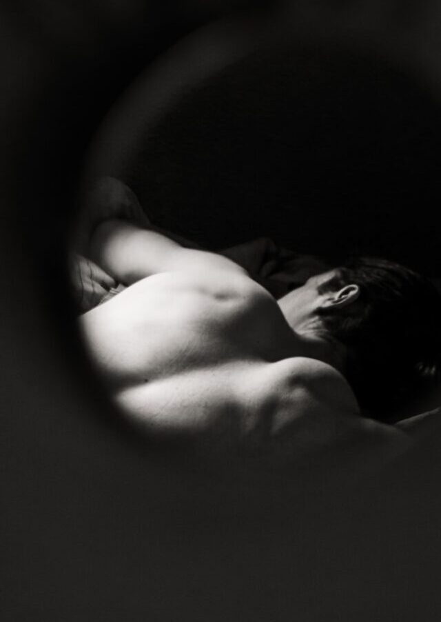 grayscale photo of woman lying on bed